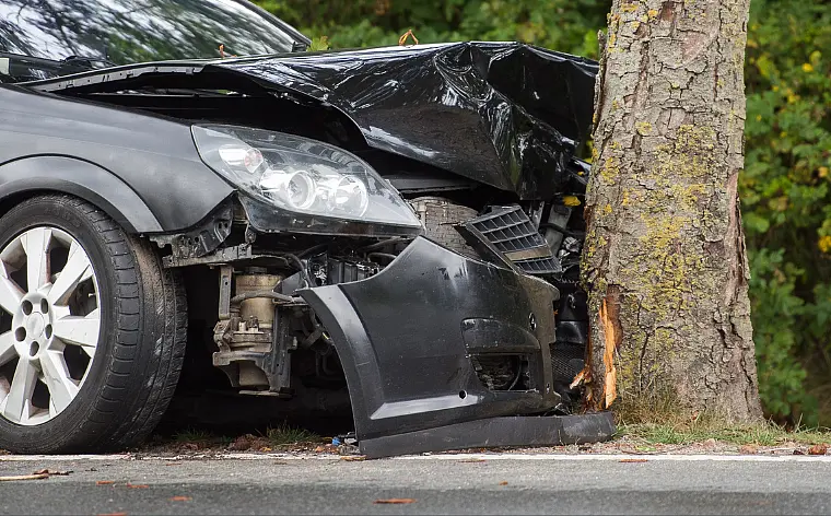 Ein Auto ist in einen Baum gefahren, die Motorhaube ist eingedrückt