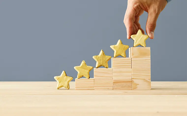 Hand setzt 5 Sterne auf eine kleine Holztreppe