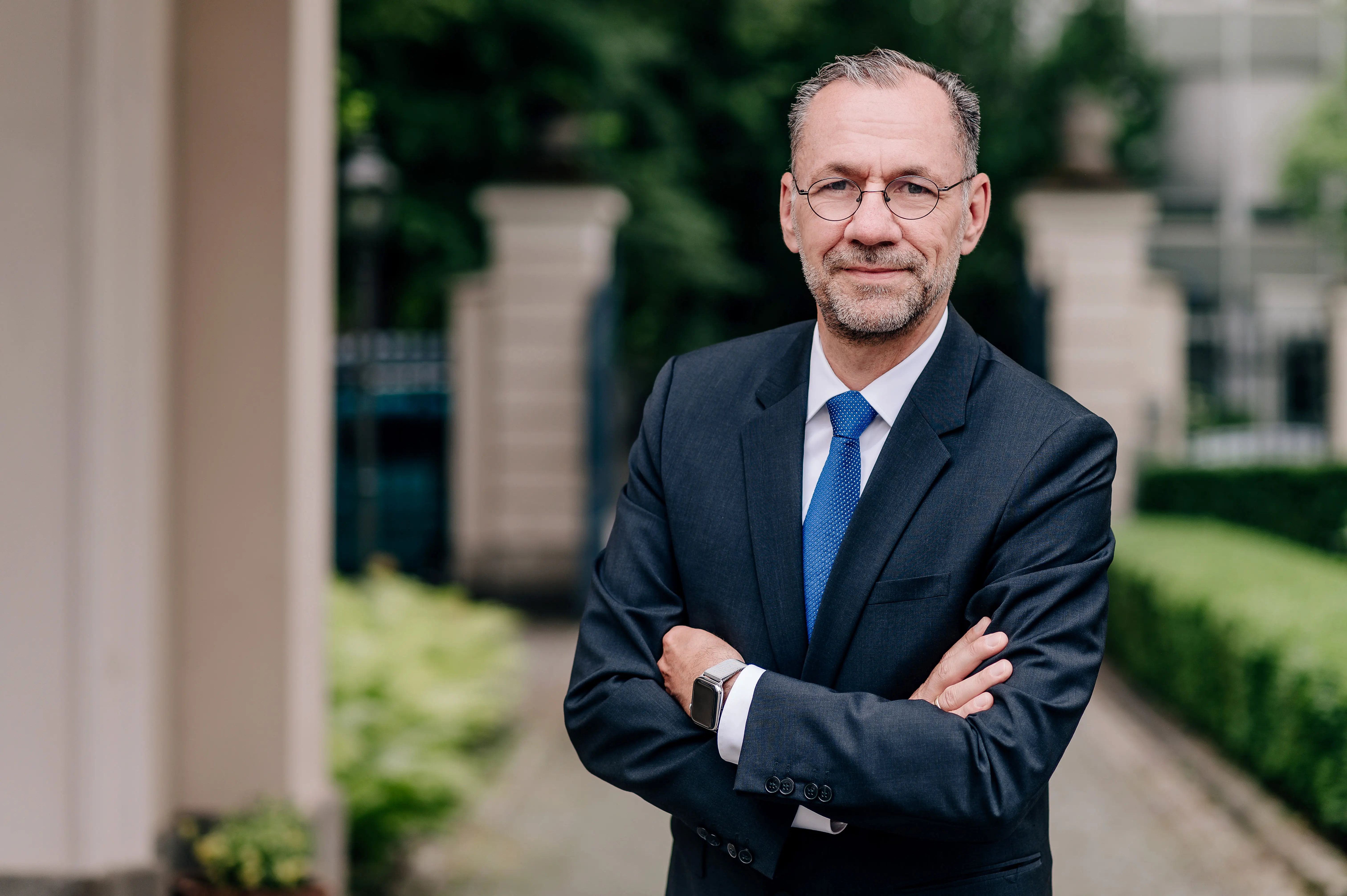 Portrait des Präsidenten und Aufsichtsratsvorsitzenden der KS/AUXILIA im Business-Anzug am Eingang des Hauptsitzes