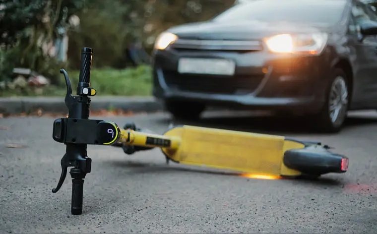 E-Scooter liegt auf einer Straße vor einem heranfahrenden Auto